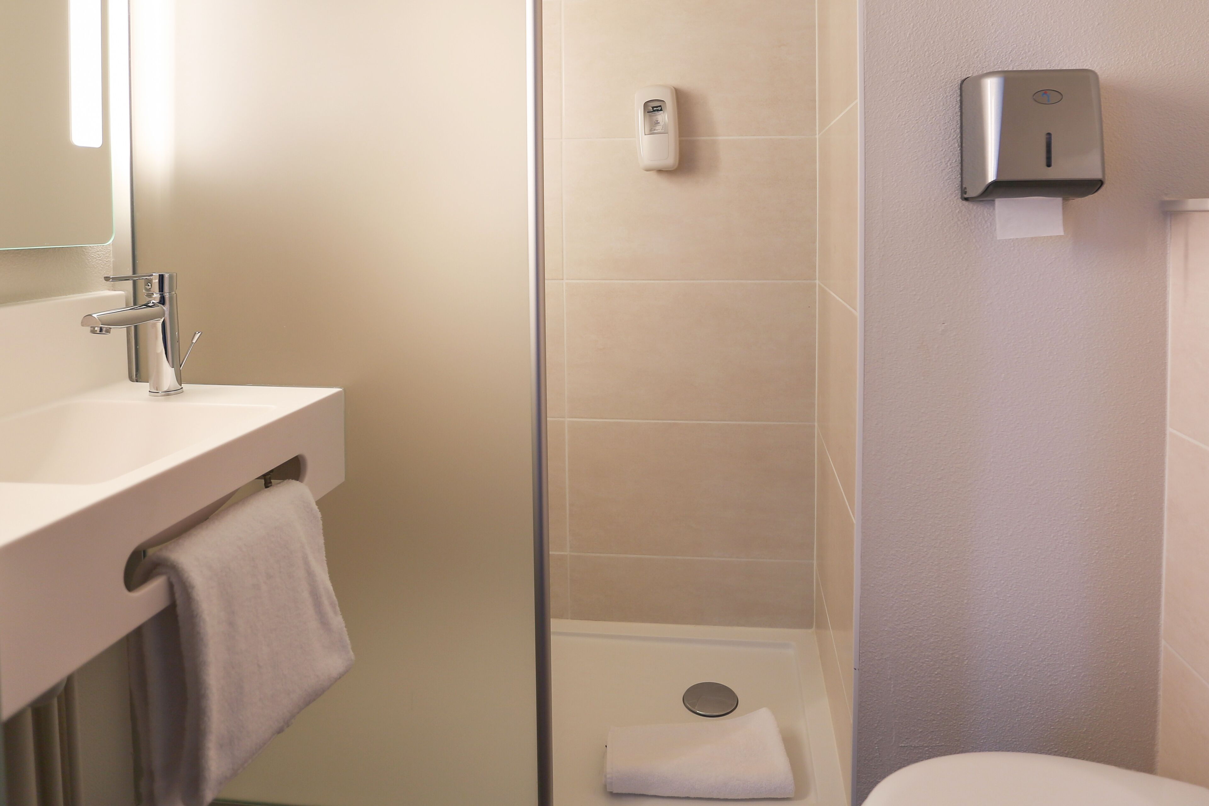 Een badkamer met een wastafel, spiegel, handdoekrek, toilet en handdroger.