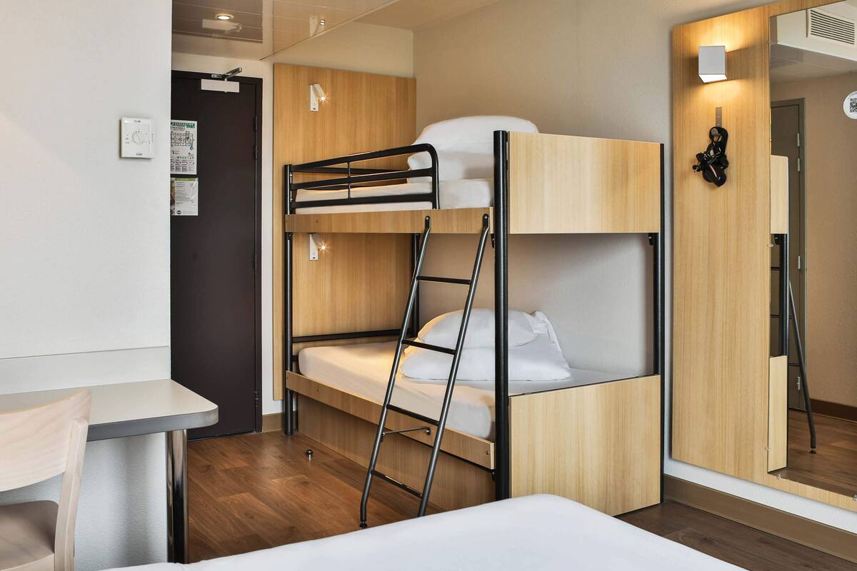 A bunk bed with a ladder, a small table, and a mirror.