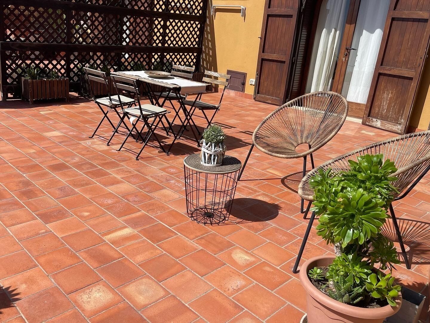 Une terrasse extérieure avec un sol carrelé, des meubles en bois et des plantes en pot.