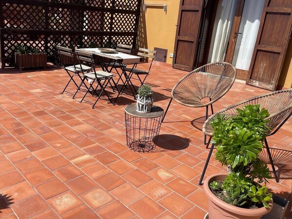 Une terrasse extérieure avec un sol carrelé, des meubles en bois et des plantes en pot.