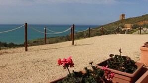 Une vue sur la côte, avec une barrière faite de cordes, des jardins aménagés en terrasses et une tour qui se dresse au loin.