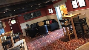 Une pièce chaleureuse avec un tapis à motifs, un canapé, une petite table et un coin bar avec des tabourets.