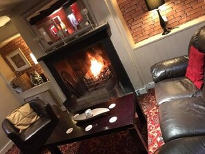 Una sala de estar acogedora con chimenea, sofá de cuero y una mesita con adornos.
