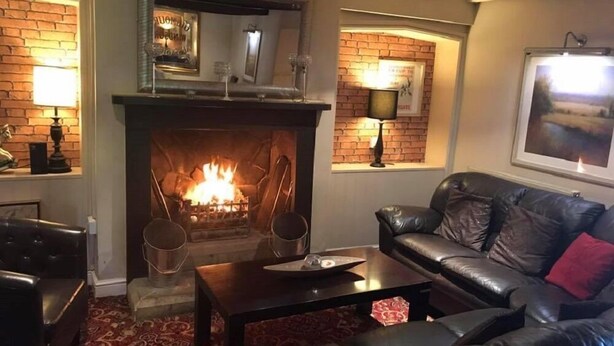 Un salon chaleureux avec une cheminée, des canapés en cuir et un tapis à motifs.