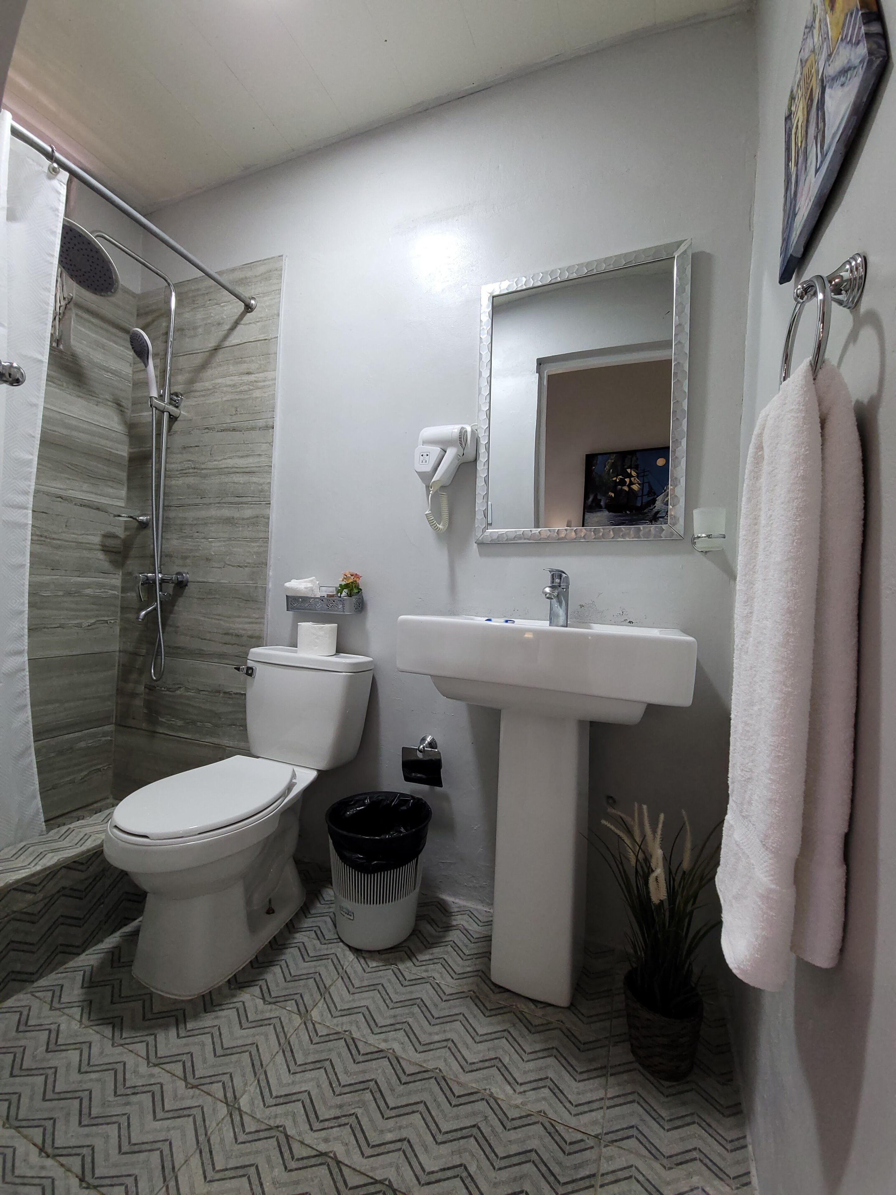 A bathroom with a shower, toilet, sink, and a towel hanging on the wall.