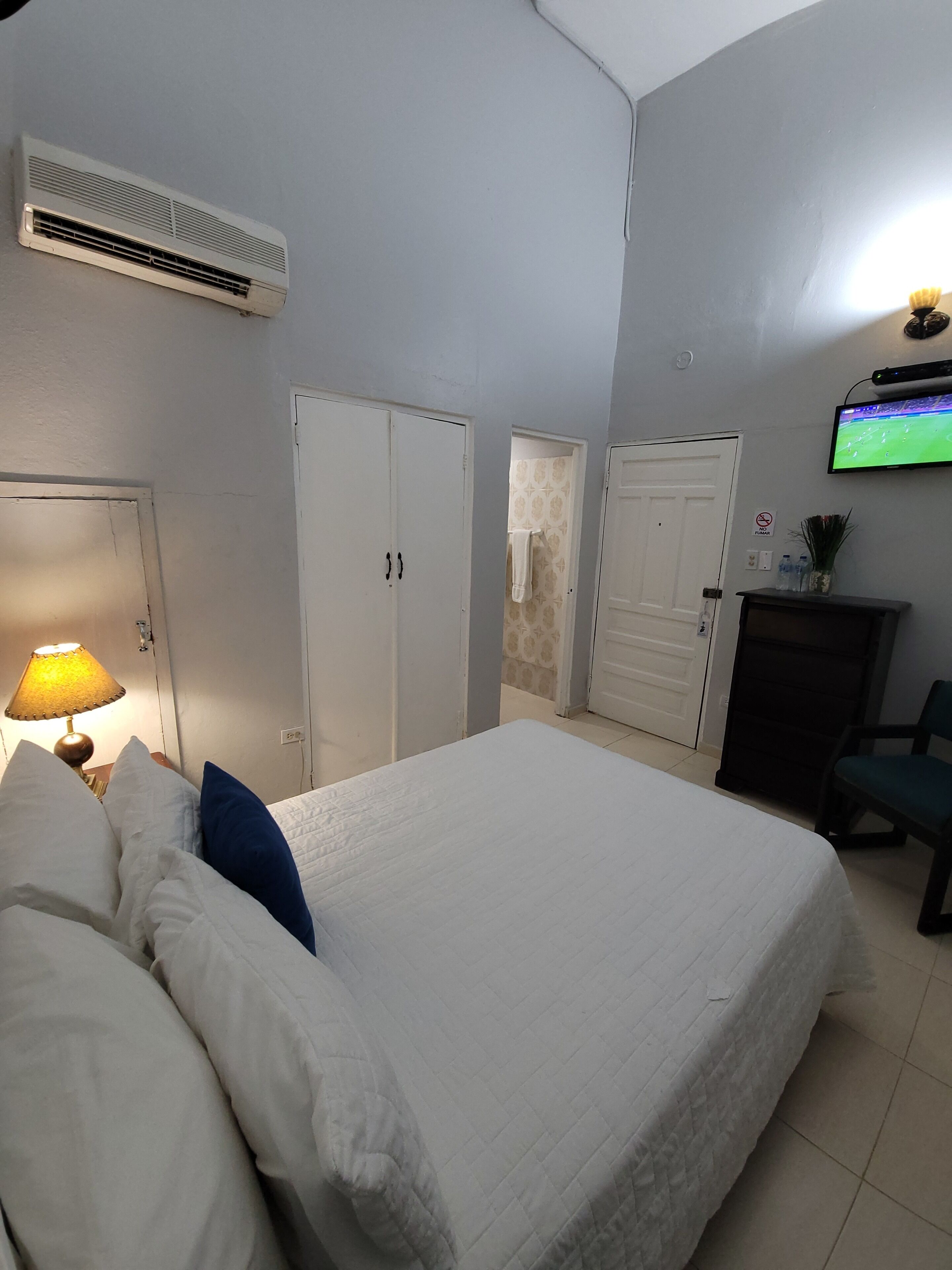 A bedroom with a bed, a TV, a desk, and a chair.