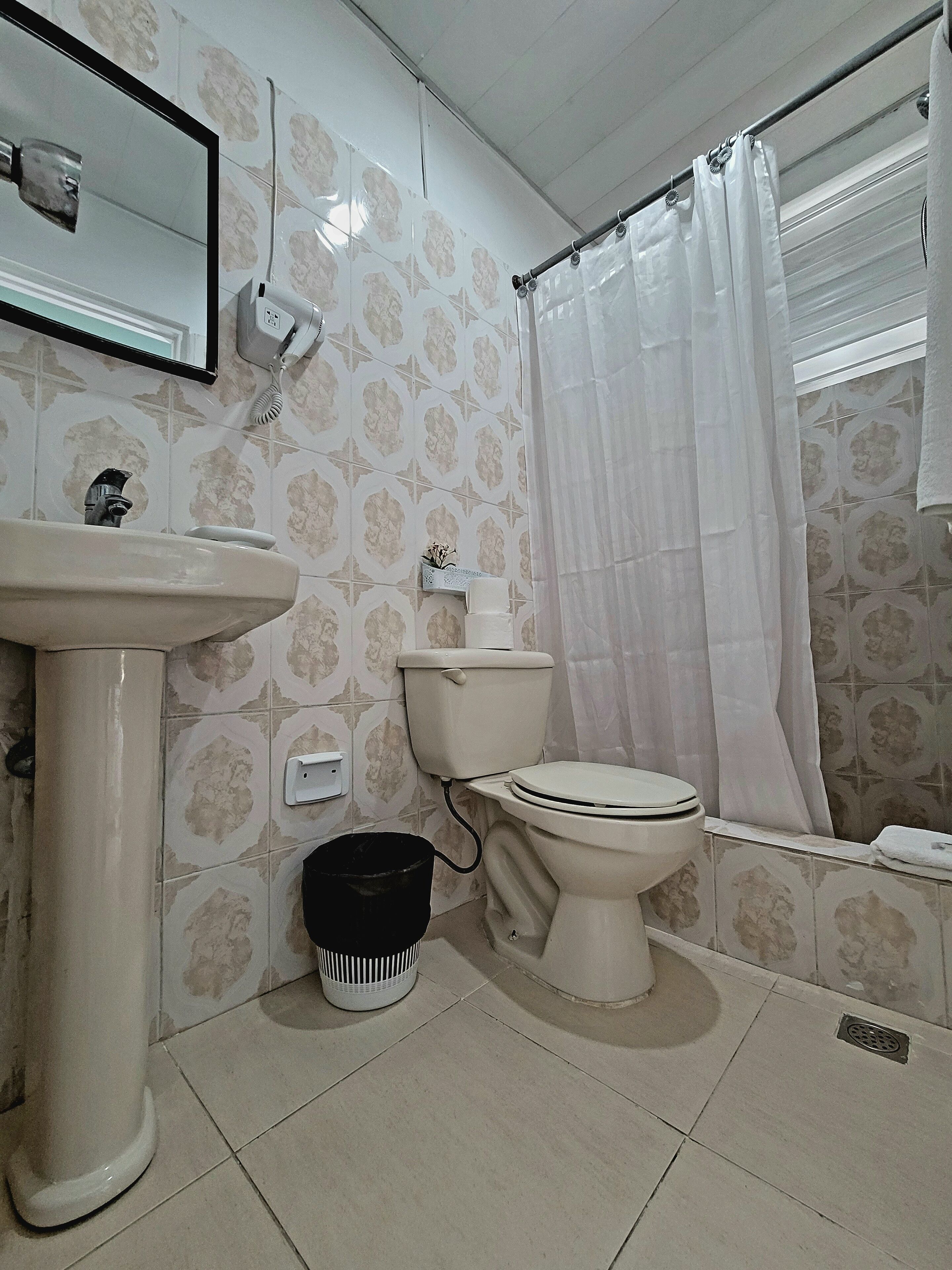 A bathroom with a toilet, sink, and shower curtain.