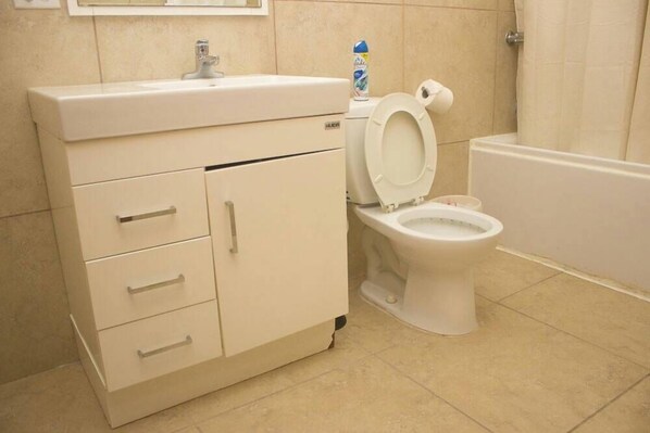A bathroom with a toilet, a sink, and a cabinet. - Duen Hotel (Port-au-Prince)