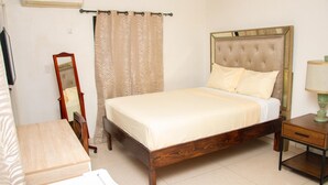 Un dormitorio con una cama de madera, una mesita de noche, un espejo y una cortina.