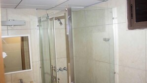 Un baño con ducha de vidrio, lavamanos y espejo.
