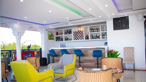 Una zona de bar con asientos, una barra con botellas y vistas al exterior.