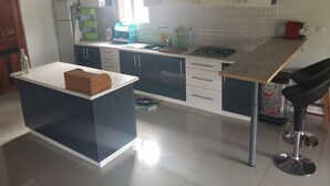A modern kitchen with a central island, white cabinets, a stove, and a sink. - The Sanctuary (Mahavelona)