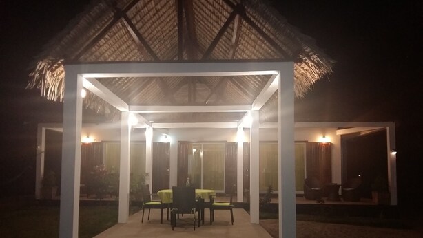 A covered outdoor seating area with tables and chairs, surrounded by a thatched-roof structure. - The Sanctuary (Mahavelona)