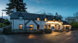 A traditional stone building with a sign for Kilchrenan Inn, a primary school, and a bench outside. - Kilchrenan Inn (Taynuilt)