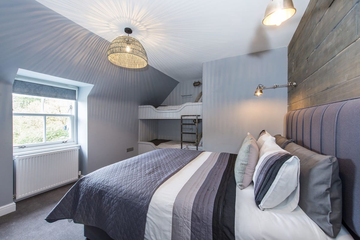 A bedroom with a bunk bed, a large window, and a ceiling light fixture.