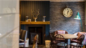 A cozy room with a fireplace, wooden furniture, and a clock on the wall. - Kilchrenan Inn (Taynuilt)