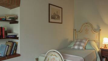 A bedroom with a bed, a nightstand, a lamp, a bookshelf, and a framed picture on the wall.