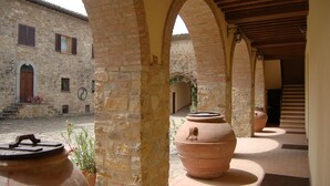 A courtyard with stone walls, large terracotta pots, and a rustic building with a wooden door. - Quercia Al Poggio (Barberino Tavarnelle)