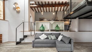 A modern living room with a grey sectional sofa, wooden flooring, and a staircase leading to an upper level. - Quercia Al Poggio (Barberino Tavarnelle)