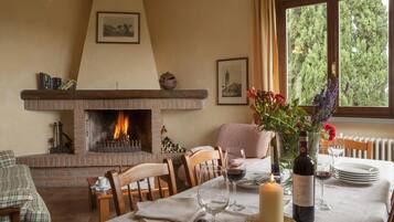A dining area with a brick fireplace, wooden furniture, and a table set for a meal.