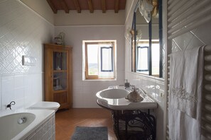 Une salle de bain avec une baignoire, un lavabo et une fenêtre.