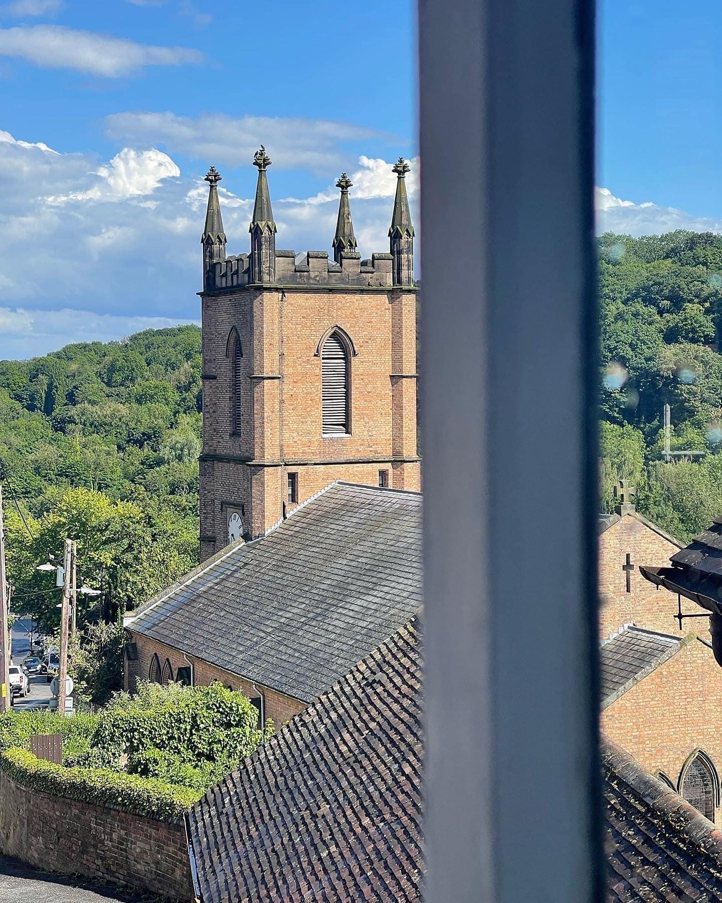 Una iglesia con una torre destacada y un edificio más pequeño con tejado de tejas.