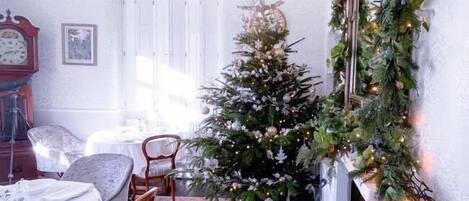 Un coin repas chaleureux, agrémenté d’un sapin de Noël, d’une horloge et d’une cheminée.