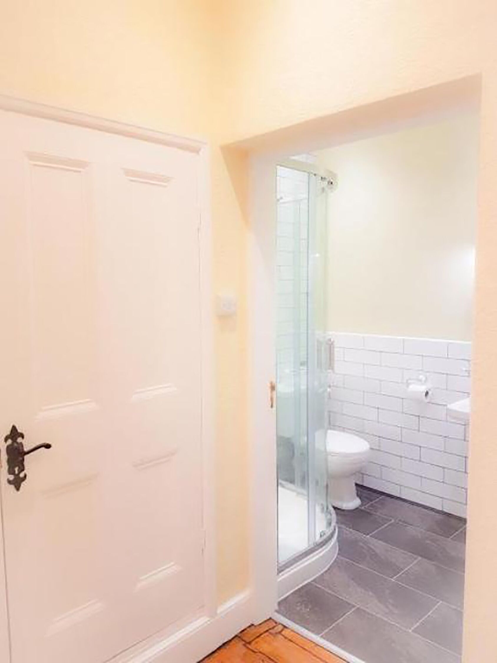 A bathroom with a white toilet, a glass shower enclosure, and a white sink.