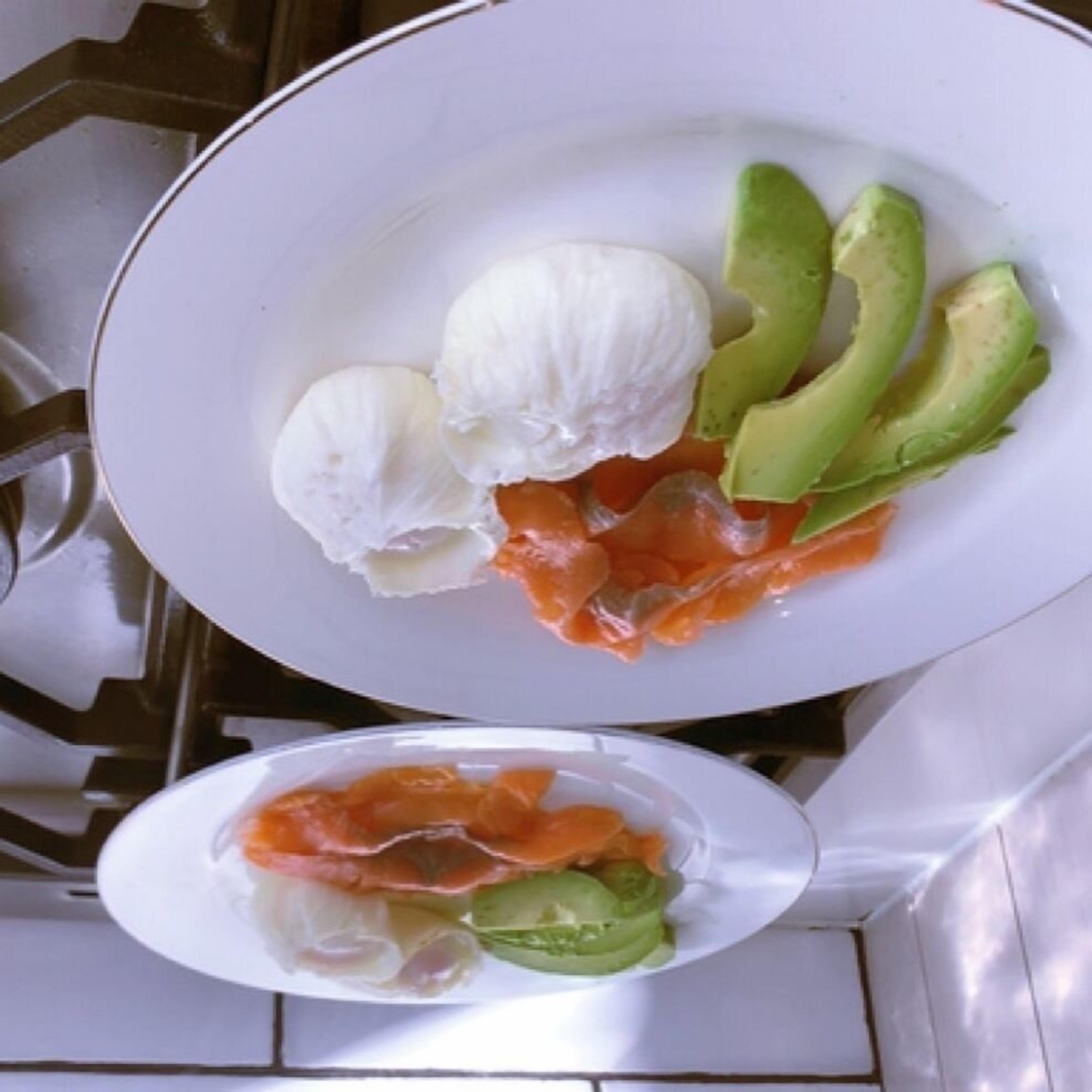 A plate with slices of avocado and smoked salmon, and a bowl of soup.