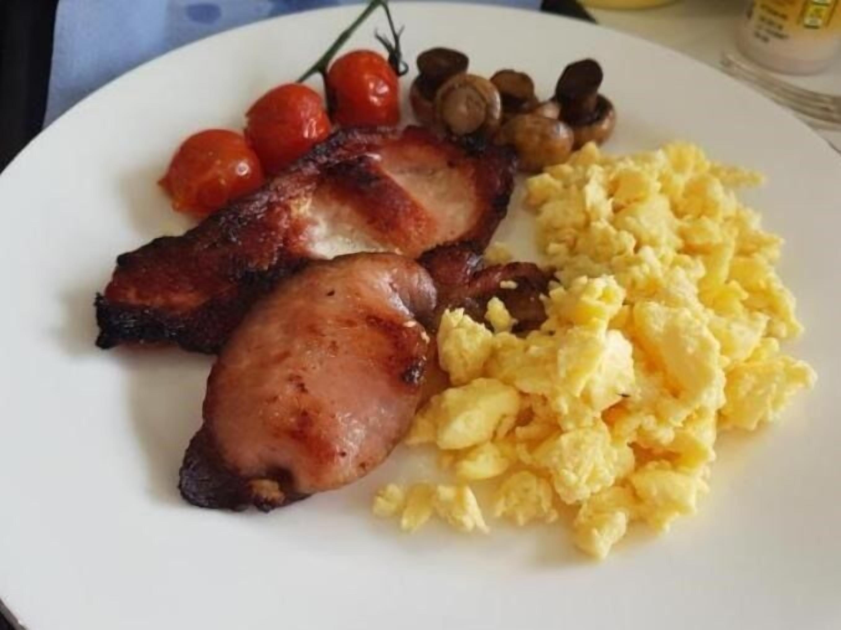 En tallerken med bacon, røræg, cherrytomater og svampe.