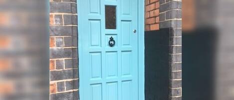 A light blue door with the number 5, set in a brick wall.