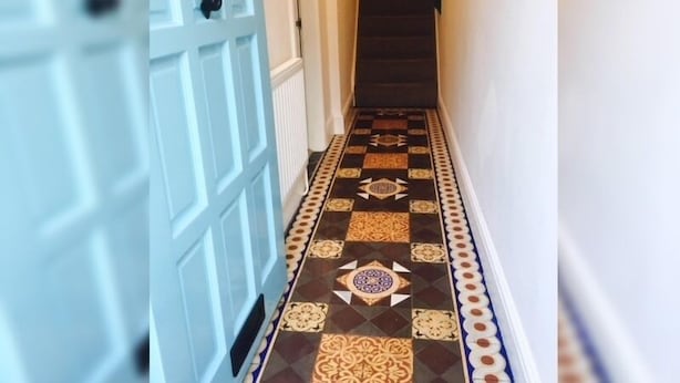 Un pasillo con piso estampado y una puerta blanca con picaporte negro.