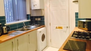 Una cocina compacta con lavadora, estufa y un reloj en la pared.
