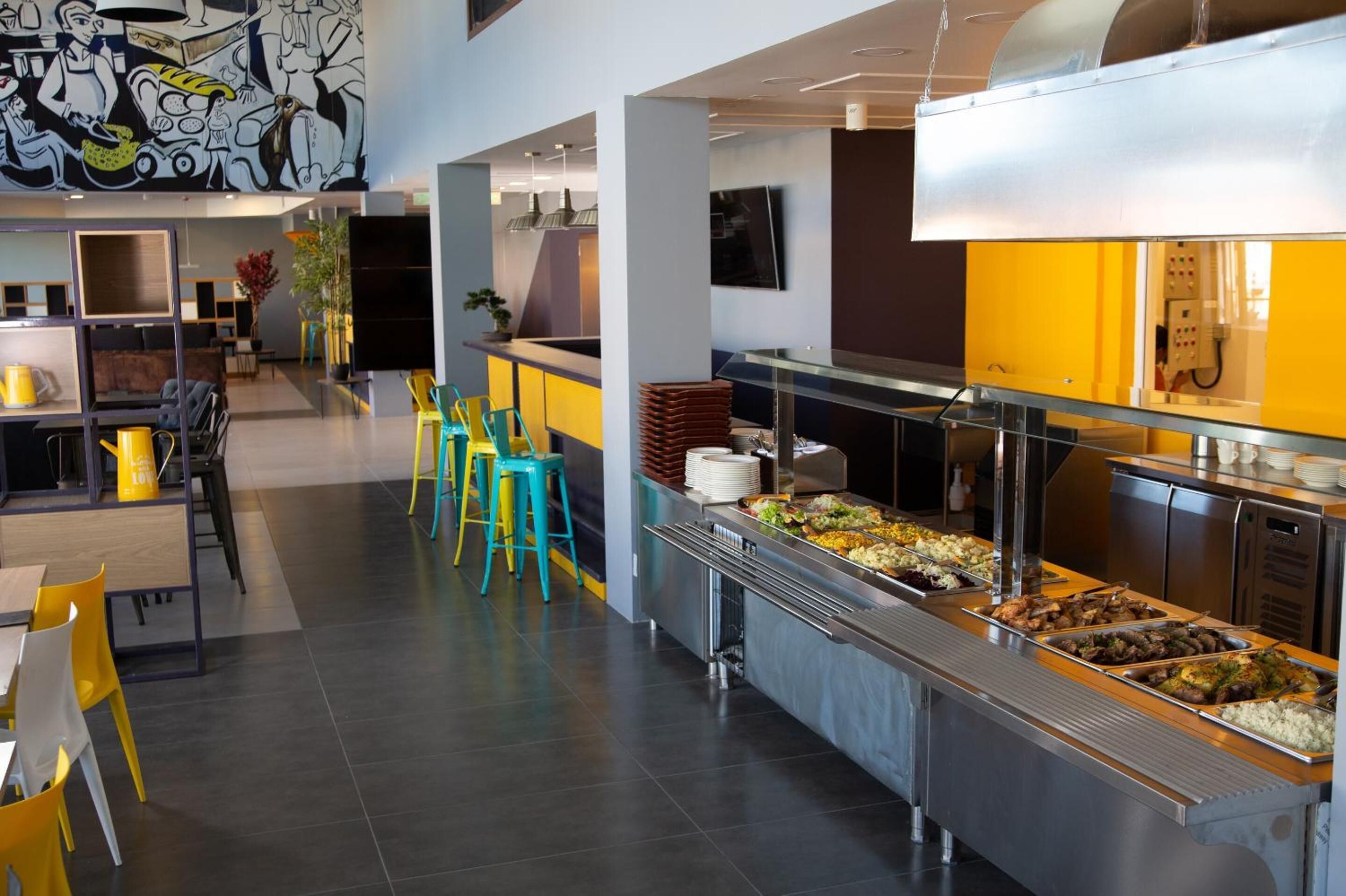 Uma cafeteria moderna com buffet, assentos no balcão e um mural na parede.