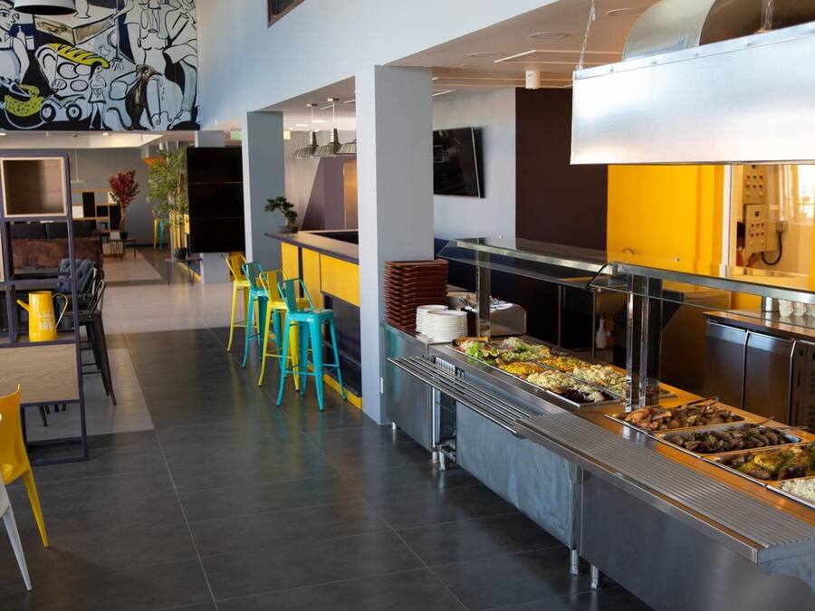 Uma cafeteria moderna com buffet, assentos no balcão e um mural na parede.