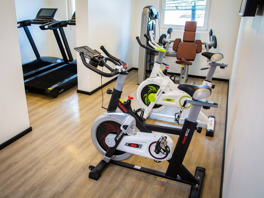 Un gimnasio con bicicletas estáticas, cinta de correr y máquina de remo.