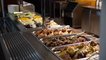 Een buffet met diverse gerechten, waaronder vlees, salades en rijst.
