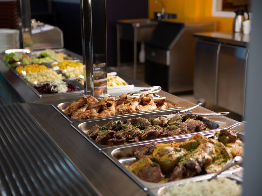 Een buffet met diverse gerechten, waaronder vlees, salades en rijst.