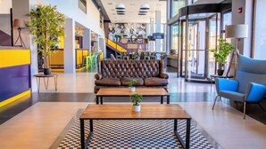 A modern lobby with a checkered floor, a leather sofa, a wooden coffee table, and a blue armchair. - Hotel Modular Express Calama (Calama)