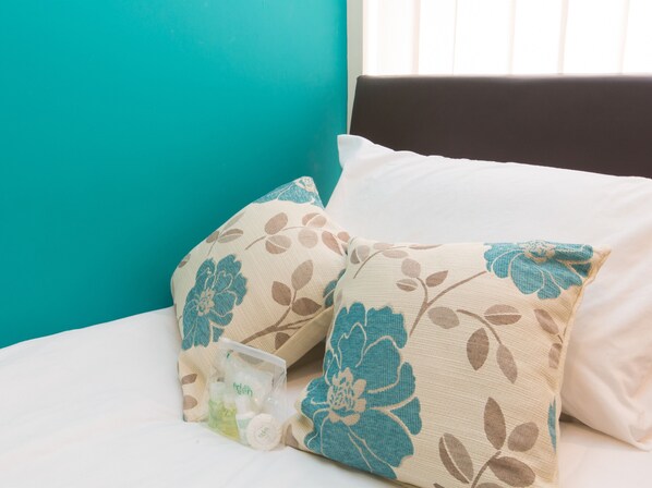 A bed with floral-patterned pillows and a plastic bag containing toiletries. - Town House @ Minshull New Road (Crewe)
