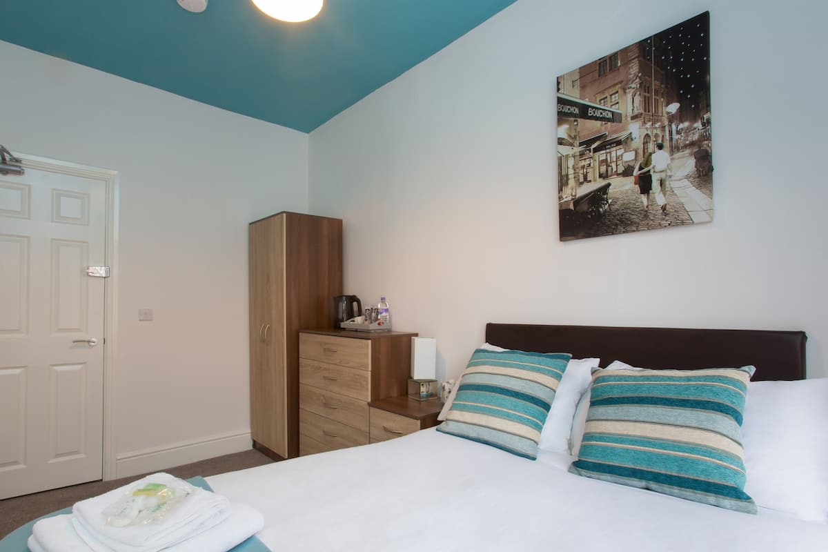 A neatly arranged bedroom with a bed, a nightstand, a wardrobe, and a wall-mounted painting.