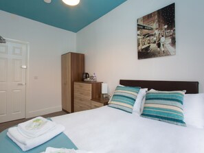 A neatly arranged bedroom with a bed, a nightstand, a wardrobe, and a wall-mounted painting. - Town House @ Minshull New Road (Crewe)