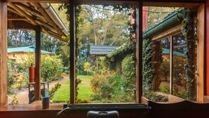 Una habitación con vista a un jardín a través de un amplio ventanal, un escritorio de madera y una máquina de escribir.