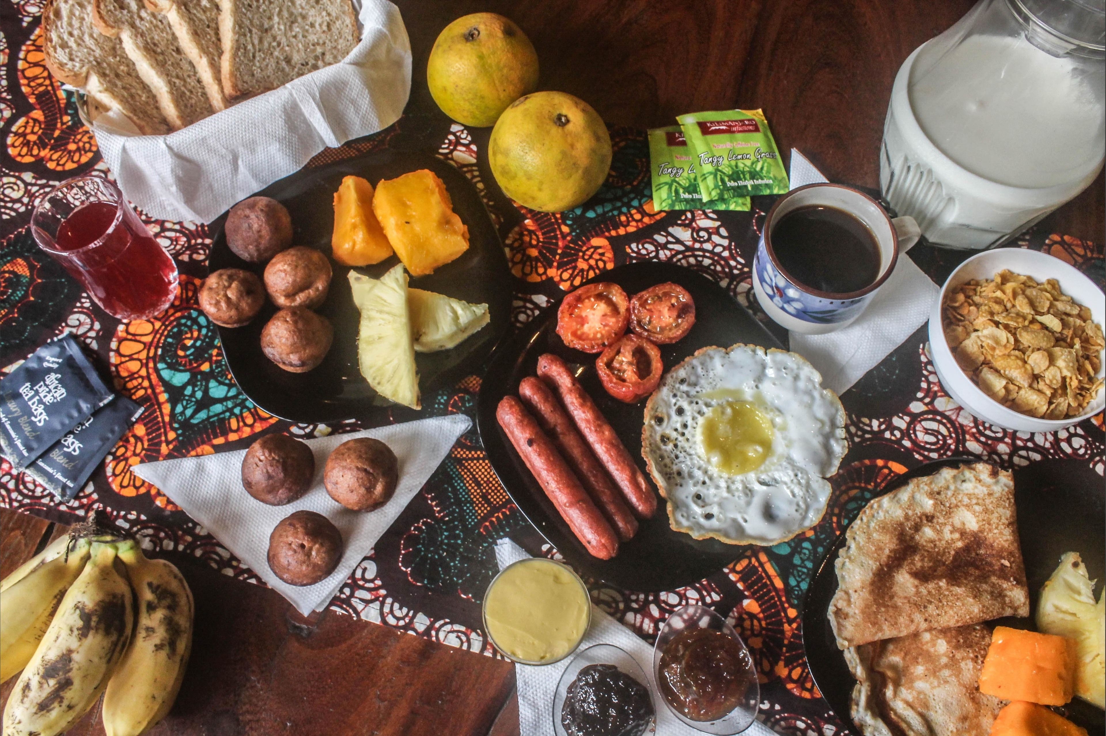 Un assortiment de produits pour le petit-déjeuner comprenant du pain, des saucisses, des œufs et diverses garnitures.