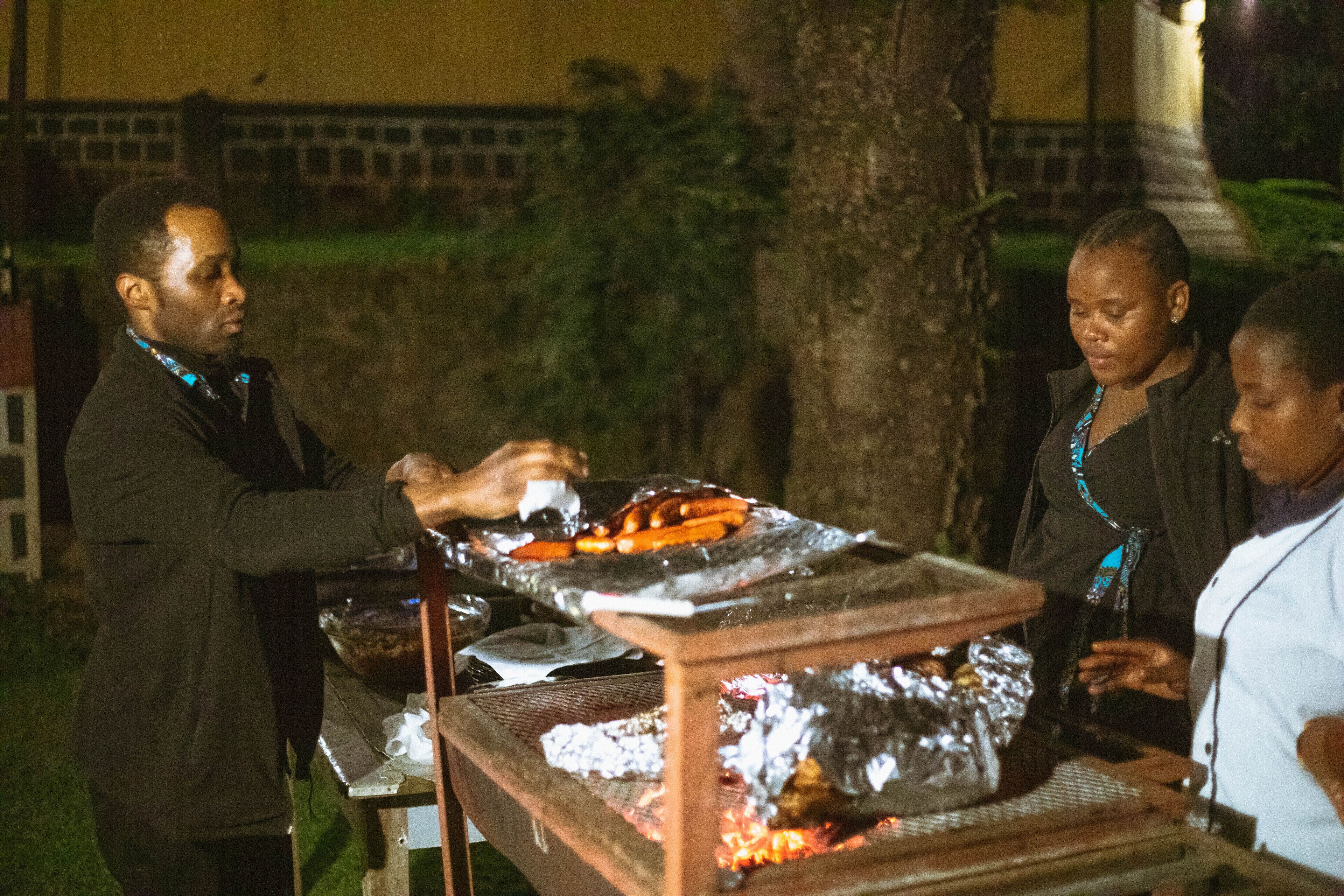A group of people cooking outdoors at night.