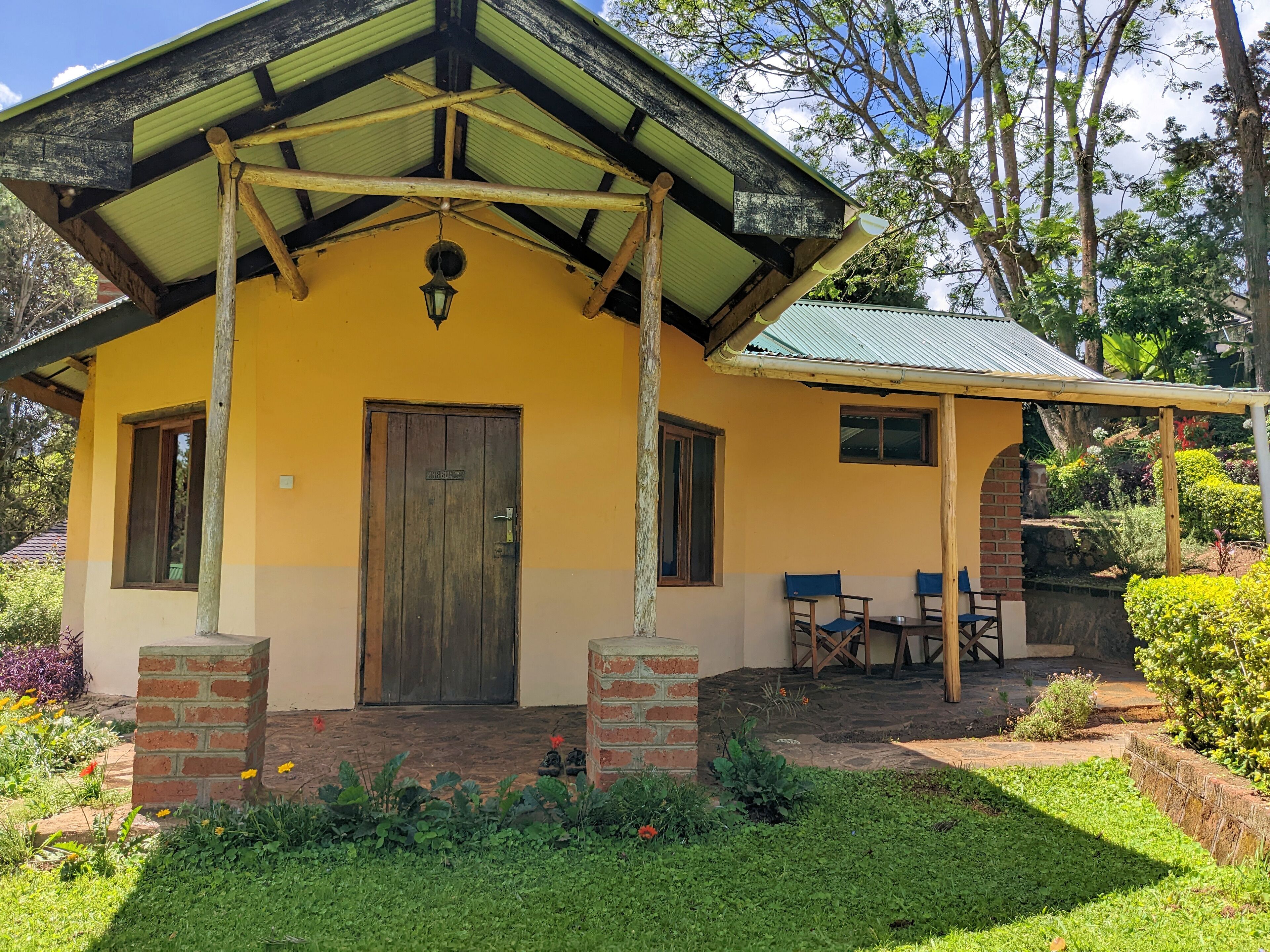 A yellow building with a wooden door and a small porch with two chairs.