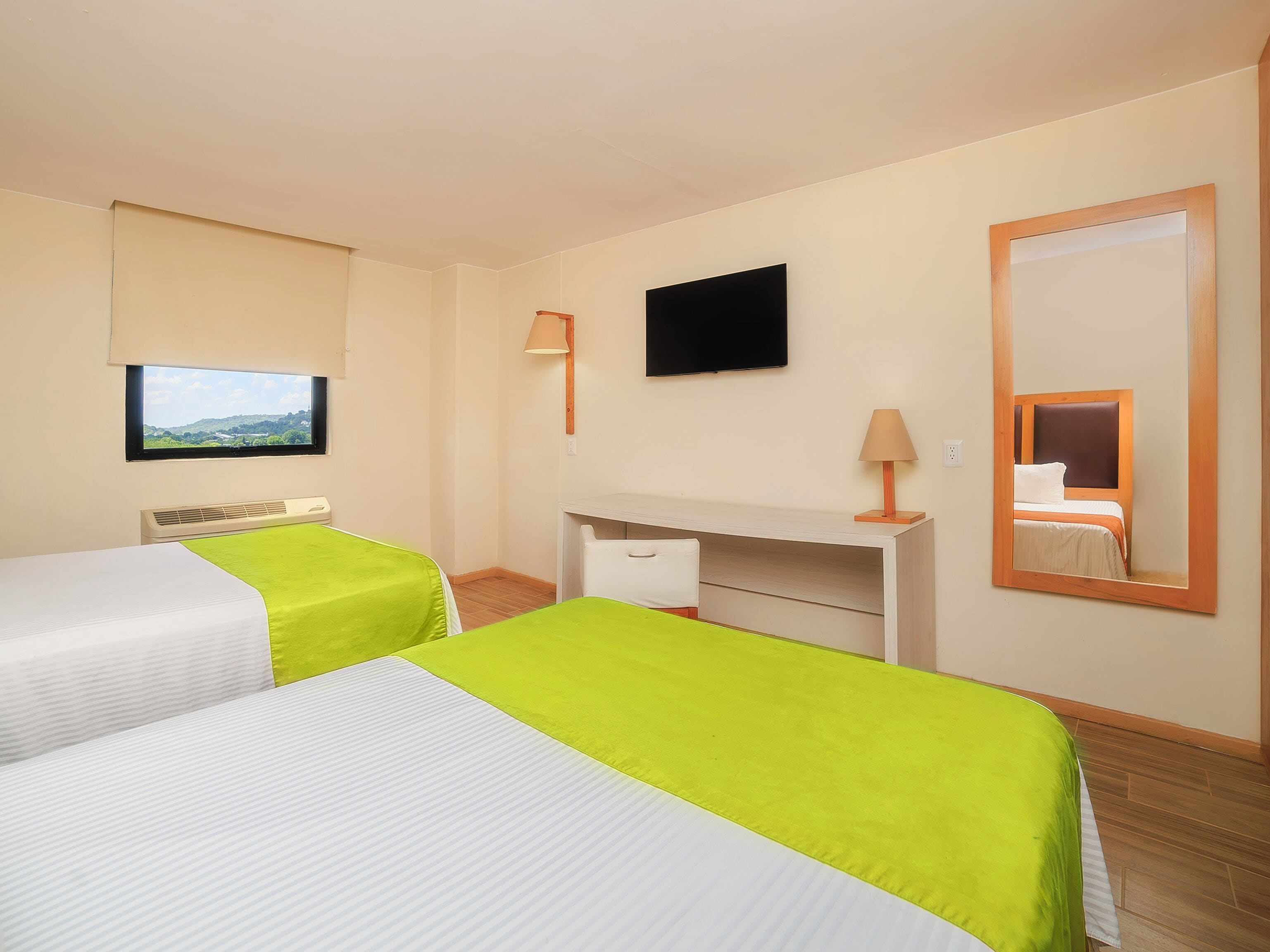 Ein Hotelzimmer mit zwei Betten, einem Schreibtisch, einem Stuhl, einem Fernseher und einem Fenster mit Blick.