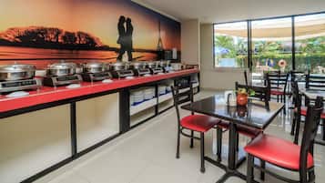 A dining area with a buffet setup, a mural of a couple, and a view of the outside.