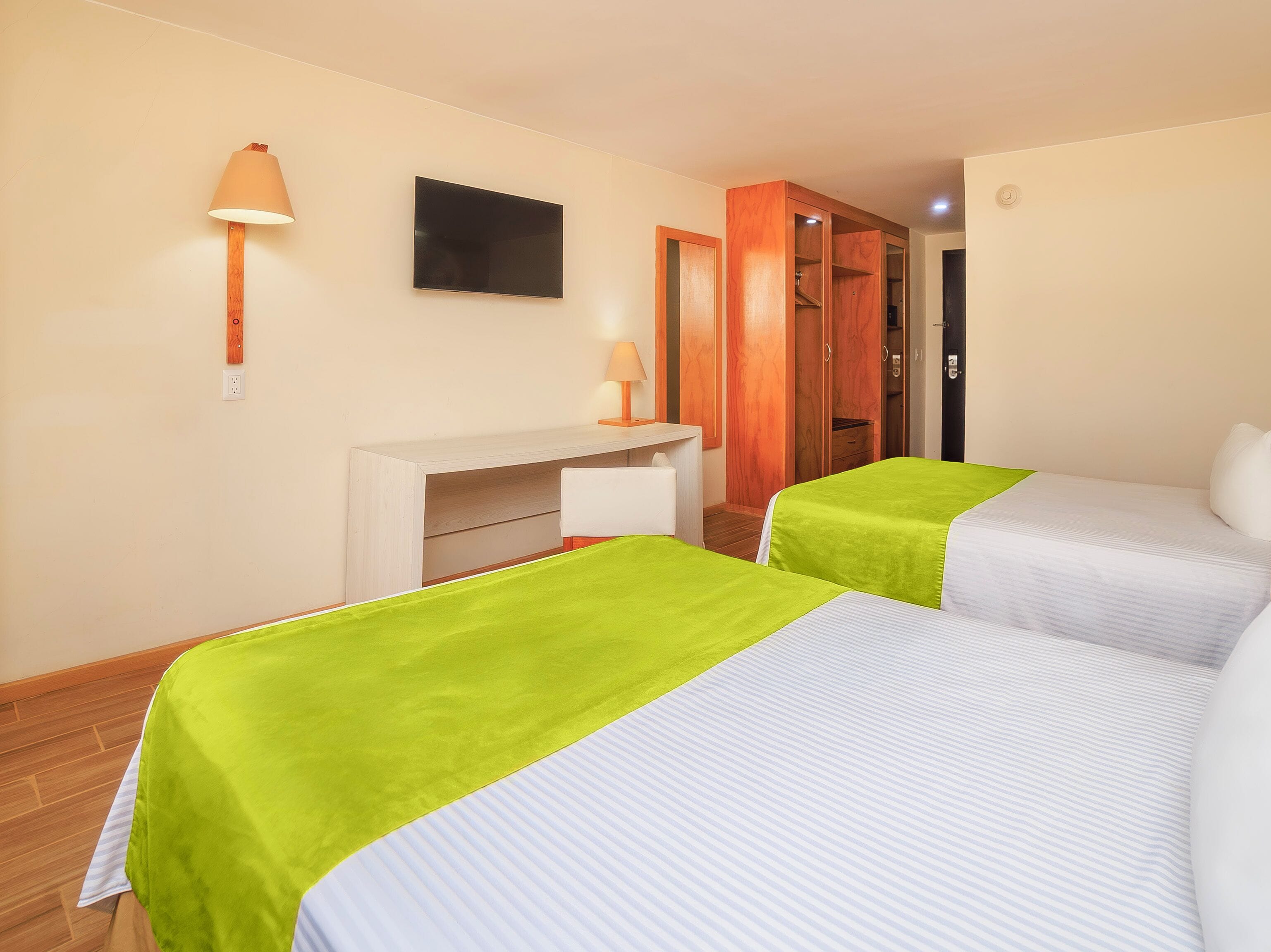 A hotel room with two beds, a TV, a desk, and a wardrobe.