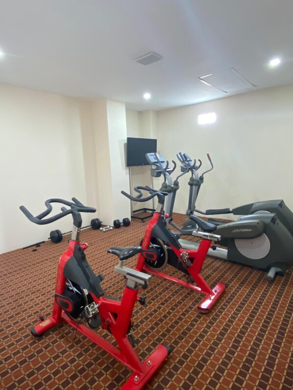 Un gimnasio con bicicletas estáticas y una cinta de correr.
